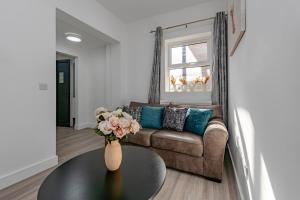 a living room with a couch and a vase with flowers on a table at The Pier Escape Sea Breaze Stay in Clacton-on-Sea