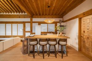 a kitchen with a wooden ceiling and a bar with stools at Luxury Hanok Blue Serenity in T'ongjin +6 photos