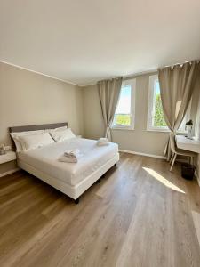 a bedroom with a large white bed and wooden floors at LE Home Soave - Locazione Turistica in Soave +15 photos