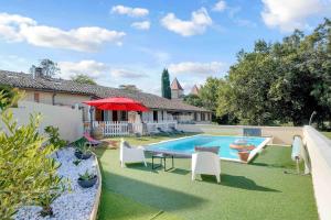 a backyard with a pool and chairs and a red umbrella at Les Chambres du Pays Toulousain in Pechbonnieu