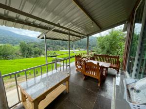 a porch with benches and a table with a view at สบายดีแม่กลางหลวง in Ban Sop Mae Klang