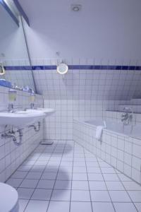 ein Badezimmer mit zwei Waschbecken und einer Badewanne und einer Toilette in der Unterkunft Waldhaus an de Miälkwellen in Ladbergen