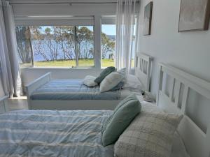 two beds in a bedroom with a large window at Bayview Luxury Waterfront Escape with Pool & Spa in Green Point +38 photos