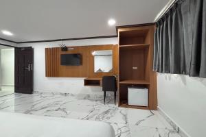 Un dormitorio con una cama, un escritorio y un televisor. en Papa Ji Hotel and Restaurant, en Bangkok
