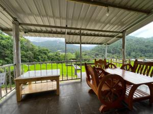 a porch with a table and chairs and a view of the mountains at สบายดีแม่กลางหลวง in Ban Sop Mae Klang