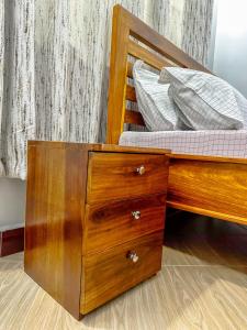 a wooden bed with a wooden dresser with a mattress at The Dar es Salaam Stay Nyumbani -1BR Urban Retreat in Dar es Salaam