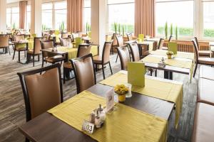 a dining room with tables and chairs and windows at Inselhotel Rote Erde in Borkum