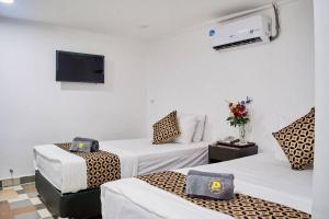 Una habitación de hotel con tres camas y un televisor. en Papa Ji Hotel and Restaurant, en Bangkok