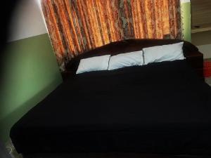 a bed with black sheets and white pillows in a room at Enyo Home in Tema