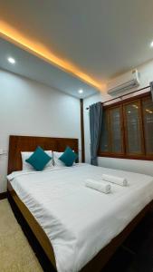 a bedroom with a large white bed with blue pillows at Siem Reap Heritage Wooden House in Siem Reap