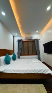 a bedroom with a large bed with blue pillows at Sala Khmer Heritage - Siem Reap Traditional Wooden House in Siem Reap +27 photos