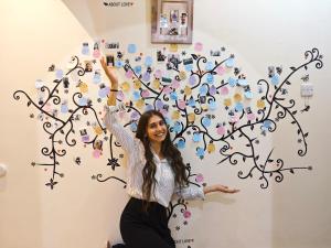 a woman standing in front of a tree mural at Su Casa Hostel in Riyadh