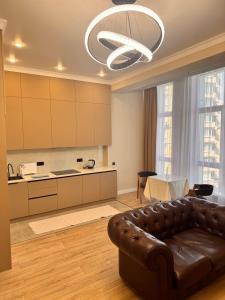 a living room with a leather couch and a kitchen at Premium Delux Astana in Zhezdi