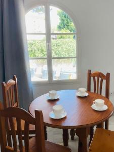 a wooden table with cups and saucers and a window at Playa Golf in Benalmádena