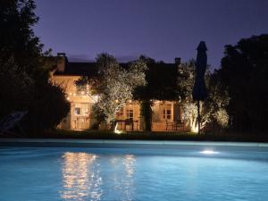 a swimming pool in front of a house at night at LA LEZARDIERE CHEZ HUGUES in Saint-Rémy-de-Provence