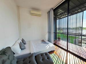 a bedroom with a bed and a large window at D Hostel by the river in Kanchanaburi City
