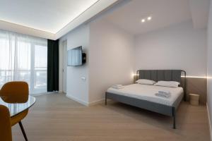 ein Schlafzimmer mit einem Bett, einem Tisch und einem Fernseher in der Unterkunft Elegant Studio Cortina Modern Stay in Voluntari