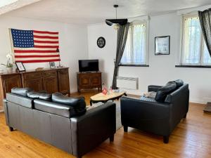 a living room with two couches and an american flag on the wall at Gîte Omaha 3 étoiles - La Ferme Delaunay in Saint-Côme-du-Mont
