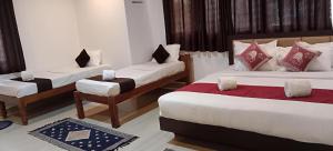 a hotel room with three beds and a chair at Giri Nele Homestay in Attigundi