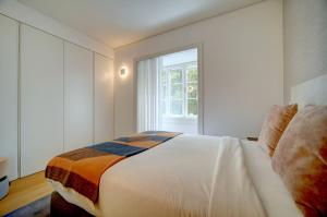 a white bedroom with a bed and a window at Mirabilis Apartments - AAA23 in Lisbon
