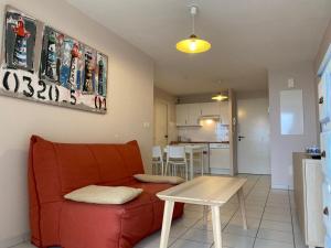 Una sala de estar con un sofá rojo y una mesa. en Appartement T2 cosy avec terrasse et parking à Vieux-Boucau - FR-1-379-65, en Vieux-Boucau-les-Bains