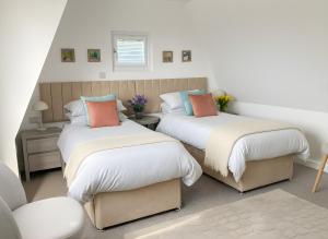 a bedroom with two beds and a chair at Seahorse in Sark