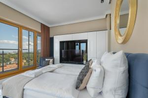 a bedroom with a white bed and a large window at Ambria Apartments Platan Tower in Świnoujście