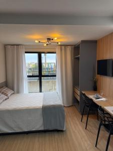 a bedroom with a bed and a desk and a window at Studio aconchegante, moderno e completo in Ponta Grossa