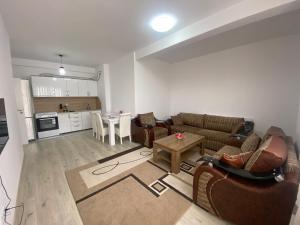a living room with couches and a table and a kitchen at Fushë Kosova Apartment in Kosovo Polje