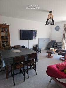 Una sala de estar con una mesa y sillas y un televisor. en Appartement à 5min du centre ville d'Embrun, en Embrun