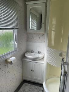 un baño con lavabo y espejo en Lovely Caravan With Large Decking Area At Southview Ref 33179S, en Winthorpe