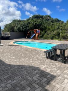 a swimming pool with a bench and a playground at Baardbos Private Game Reserve in Stilbaai