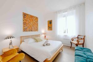 a white bedroom with a bed and a chair at Les coques bleues in Granville