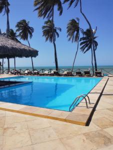 a swimming pool with palm trees and the ocean at Eco paradise 226 in Cumbuco