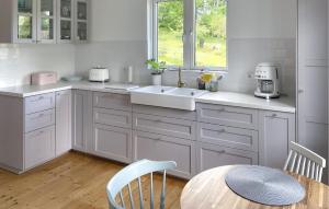 a kitchen with white cabinets and a sink and a table at Nice Home In Edsbruk With Kitchen in Edsbruk