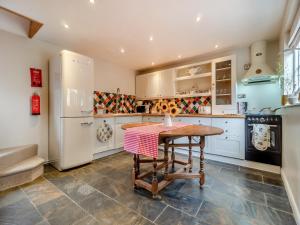 a kitchen with a table and a refrigerator at All Saints Cottage in Saffron Walden