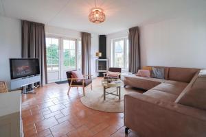 a living room with a couch and a tv at Beachvilla - 8 people in Makkum