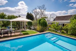 a swimming pool with an umbrella next to a house at Old Village Lodge in McGregor