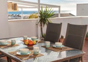 a table with a bowl of fruit on it with a view of the beach at La Triniá in Conil de la Frontera +11 photos