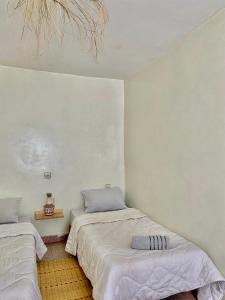 two beds in a room with white walls at Titryte Hostel - chill rooftop in Aourir +26 photos