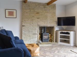 a living room with a blue couch and a fireplace at Seamstress Cottage in Ripponden