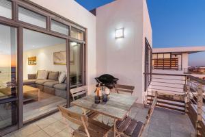 a living room with a table and chairs and a couch at Eden on The Bay 250 in Bloubergstrand