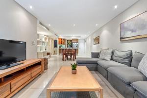 a living room with a couch and a tv at Eden on The Bay 250 in Bloubergstrand