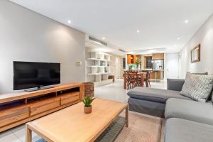 a living room with a couch and a flat screen tv at Eden on The Bay 250 in Bloubergstrand +40 photos