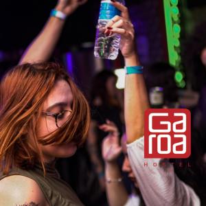 a woman holding a bottle of water in the air at Garoa Hostel Party Bar in São Paulo