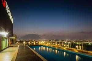 a hotel swimming pool with a view of a city at night at Fiesta Inn Monterrey Fundidora in Monterrey