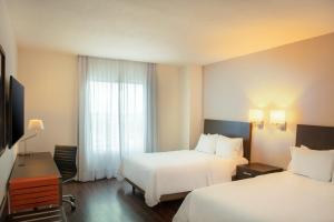 a hotel room with two beds and a window at Fiesta Inn Monterrey Fundidora in Monterrey +38 photos