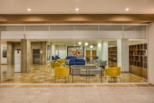 a lobby with yellow chairs and a library at Fiesta Inn Guadalajara Periferico Poniente in Guadalajara