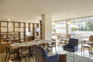 a dining room with tables and chairs and windows at Fiesta Inn Guadalajara Periferico Poniente in Guadalajara