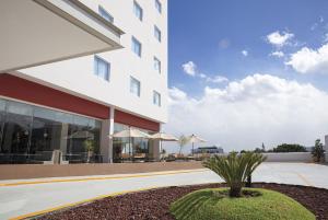 a building with a palm tree in front of it at Fiesta Inn Guadalajara Periferico Poniente in Guadalajara